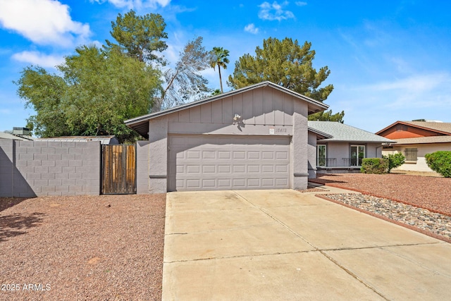view of front of property featuring board and batten siding, driveway, a gate, a garage, and fence