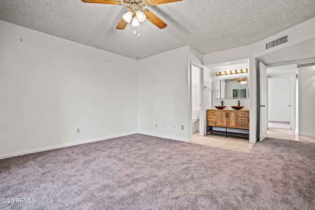 unfurnished bedroom featuring carpet floors, baseboards, a textured ceiling, and visible vents