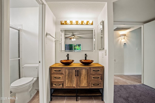 bathroom with a ceiling fan, tile patterned flooring, vanity, toilet, and a shower with door