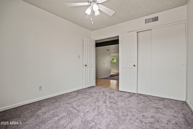 unfurnished bedroom with a textured ceiling, visible vents, carpet floors, baseboards, and a closet
