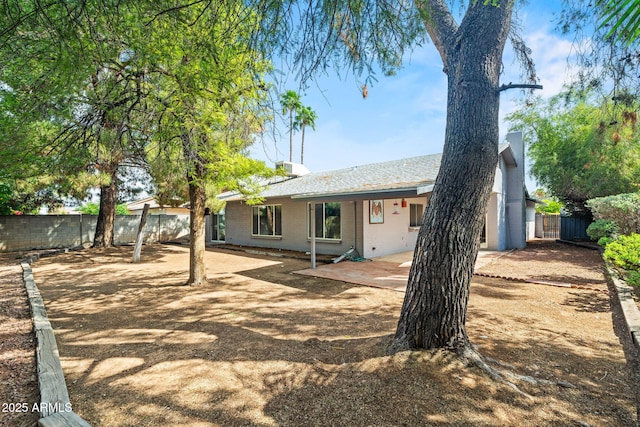rear view of property featuring a patio, a fenced backyard, a chimney, and brick siding
