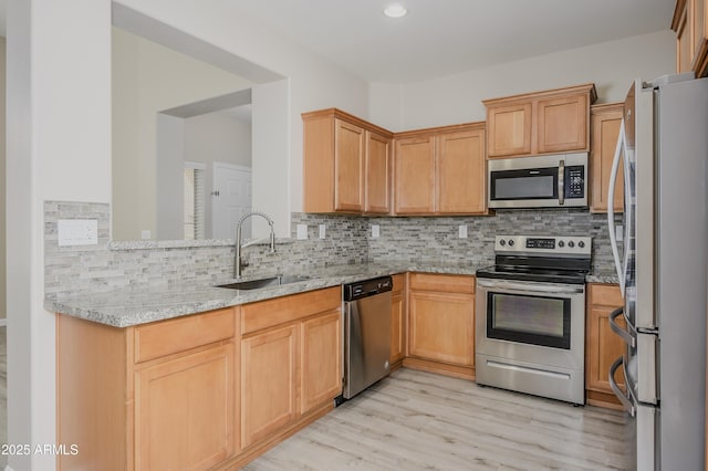 41715 N Raleigh Ct, Anthem, AZ 85086 - kitchen with appliances with stainless steel finishes, a sink, light wood finished floors, tasteful backsplash, and light stone countertops