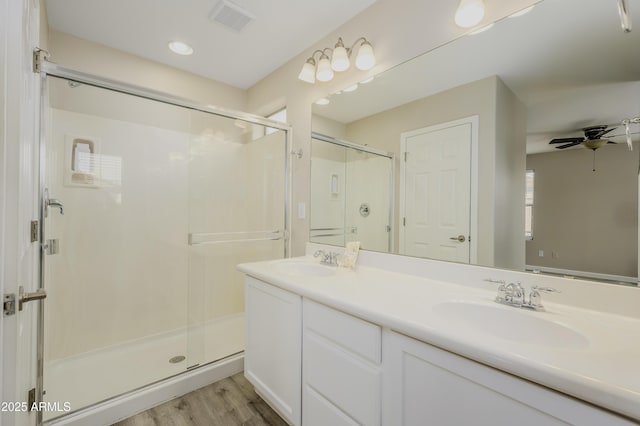 41715 N Raleigh Ct, Anthem, AZ 85086 - bathroom featuring double vanity, a stall shower, wood finished floors, and a ceiling fan