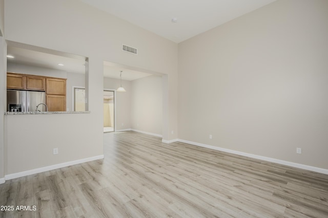 41715 N Raleigh Ct, Anthem, AZ 85086 - unfurnished living room with light wood finished floors, baseboards, and a sink