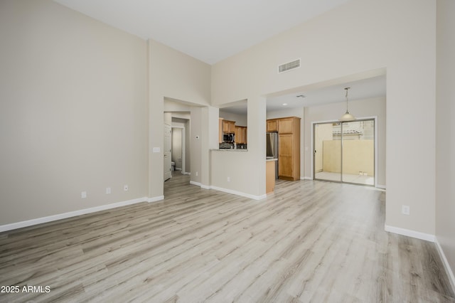 41715 N Raleigh Ct, Anthem, AZ 85086 - unfurnished living room with light wood-style flooring, baseboards, and a high ceiling