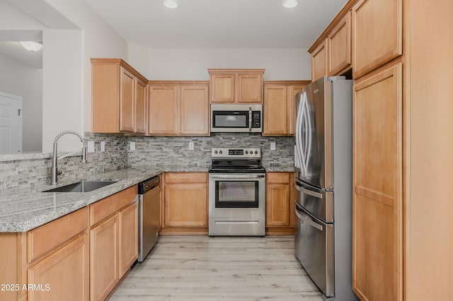 41715 N Raleigh Ct, Anthem, AZ 85086 - kitchen featuring stainless steel appliances, a sink, light stone counters, light wood-style flooring, and backsplash