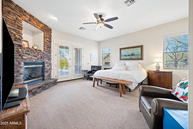 carpeted bedroom featuring access to exterior, a stone fireplace, french doors, and ceiling fan