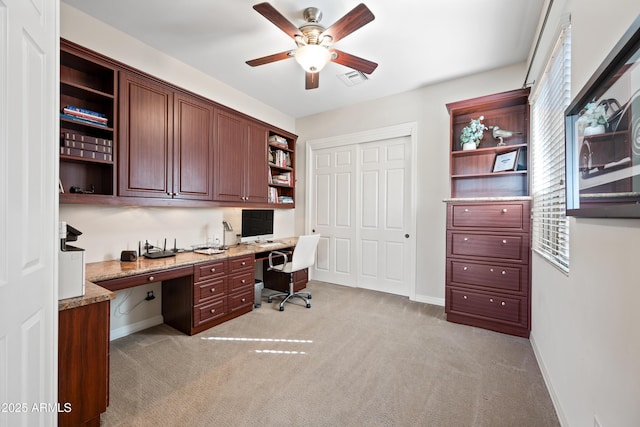 office space with light carpet, built in desk, and ceiling fan