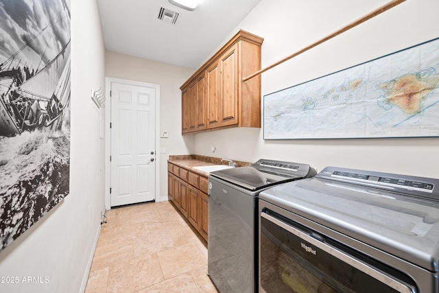 clothes washing area with cabinets, washing machine and clothes dryer, and sink