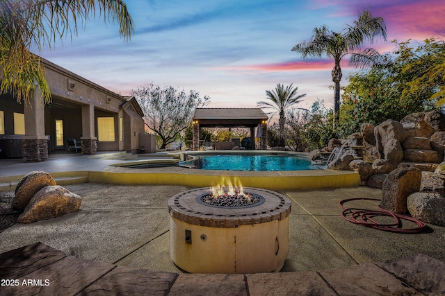 pool at dusk with a gazebo, an outdoor fire pit, and a patio