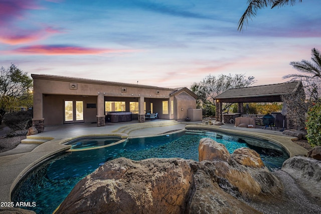 pool at dusk with a gazebo, a patio area, an outdoor bar, and an in ground hot tub