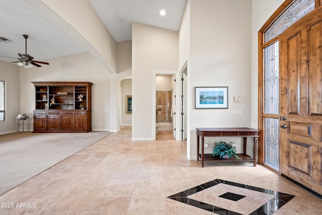 carpeted entryway with a towering ceiling and ceiling fan