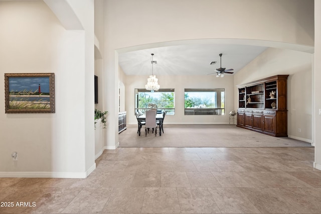 interior space featuring high vaulted ceiling and ceiling fan with notable chandelier