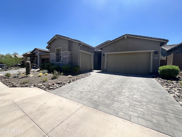 view of front of home featuring a garage, stone siding, a tile roof, decorative driveway, and stucco siding