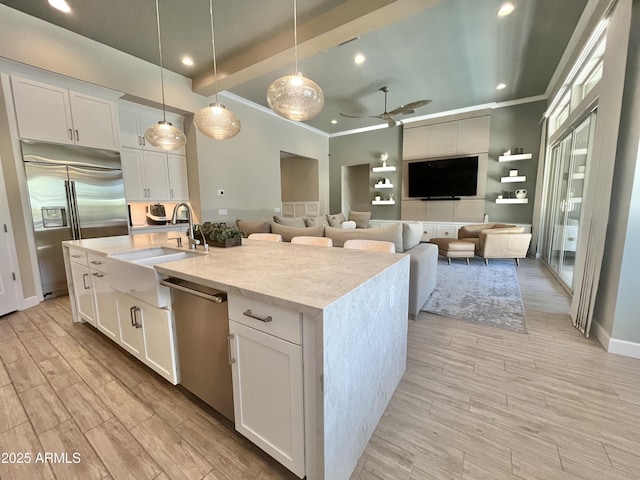 kitchen featuring white cabinets, an island with sink, appliances with stainless steel finishes, wood tiled floor, and a sink