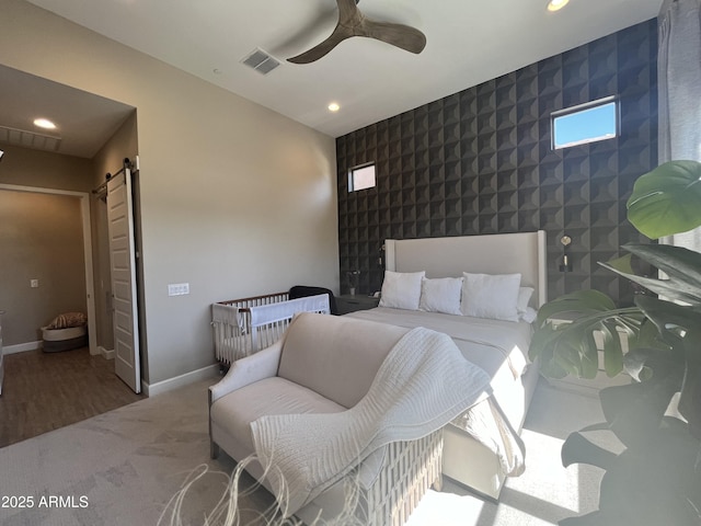 carpeted bedroom with recessed lighting, visible vents, a barn door, an accent wall, and baseboards