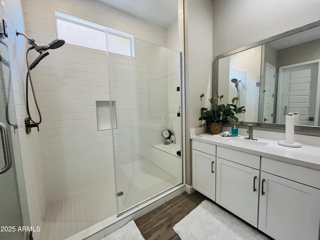 full bathroom featuring a stall shower, wood finished floors, and vanity