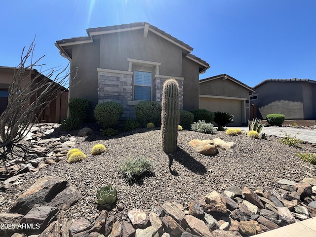 view of front of house with a garage, a tile roof, stone siding, driveway, and stucco siding