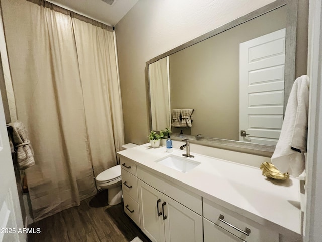 bathroom featuring toilet, curtained shower, wood finished floors, and vanity