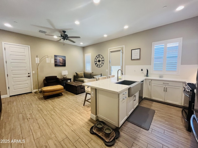 kitchen with stainless steel appliances, recessed lighting, light wood-style flooring, a sink, and a peninsula