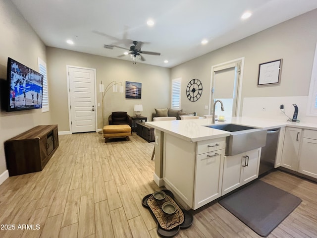 kitchen featuring recessed lighting, light countertops, stainless steel dishwasher, open floor plan, and light wood-type flooring