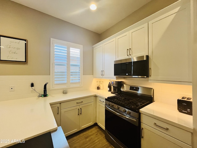 kitchen featuring light countertops, appliances with stainless steel finishes, dark wood-type flooring, and white cabinets