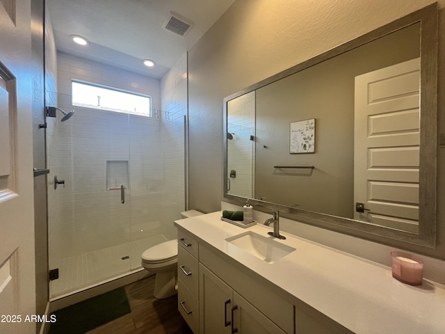 full bathroom featuring a stall shower, visible vents, toilet, wood finished floors, and vanity