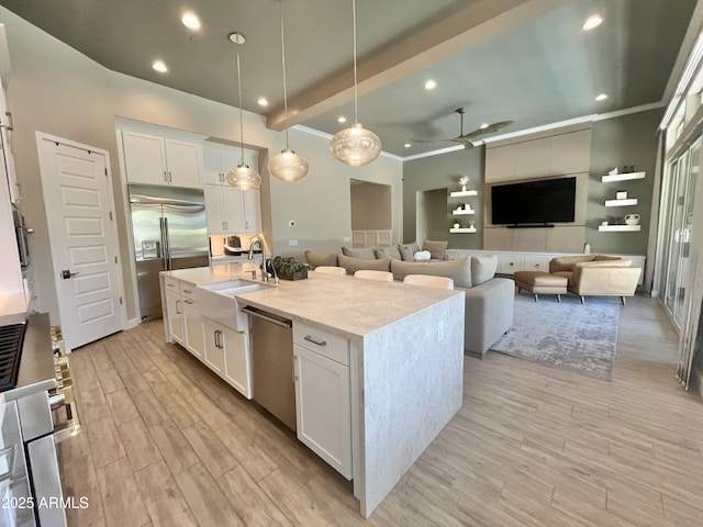 kitchen featuring appliances with stainless steel finishes, white cabinets, a kitchen island with sink, and light wood finished floors