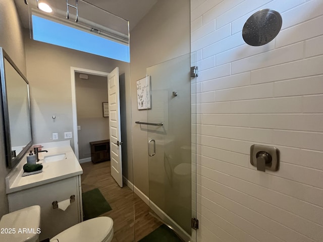 full bath featuring a stall shower, baseboards, toilet, wood finished floors, and vanity