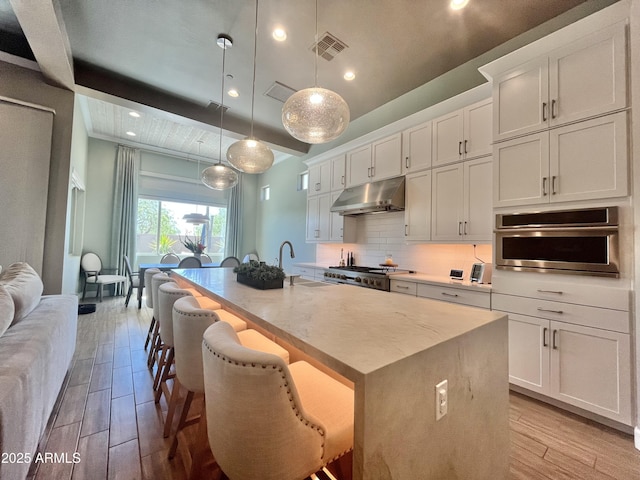 kitchen featuring visible vents, light wood-style floors, oven, and under cabinet range hood