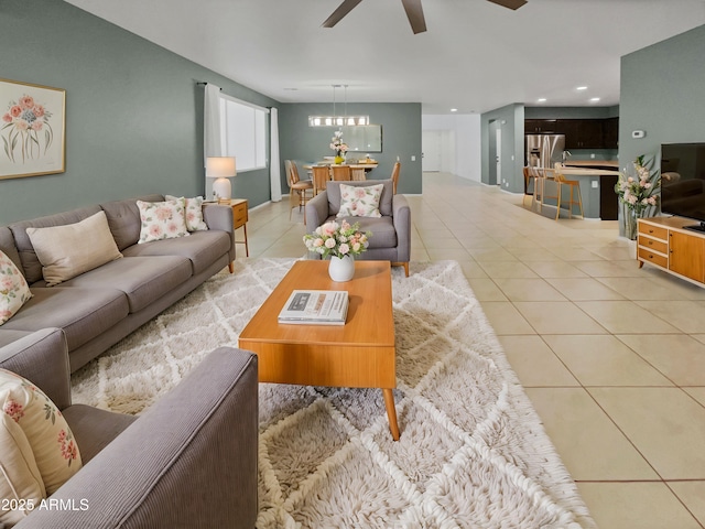 tiled living room with ceiling fan with notable chandelier