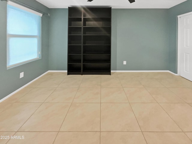 tiled spare room with ceiling fan