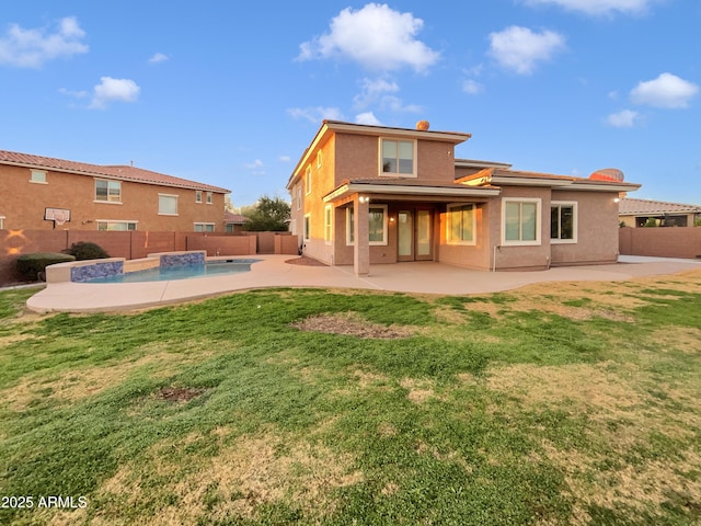 rear view of property with a patio area, a fenced in pool, and a yard