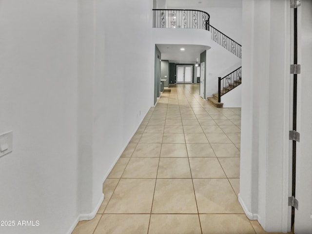 corridor featuring light tile patterned flooring and a towering ceiling