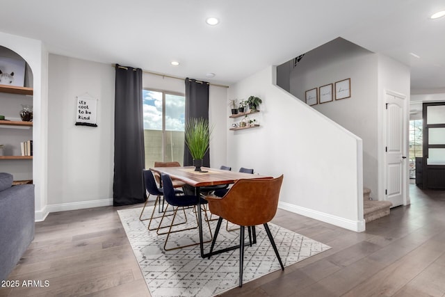 dining space featuring baseboards, stairway, wood finished floors, and recessed lighting