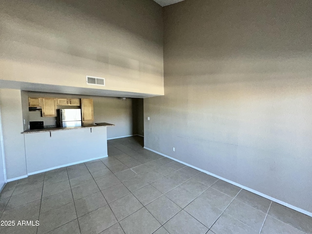 empty room with tile patterned flooring and a high ceiling