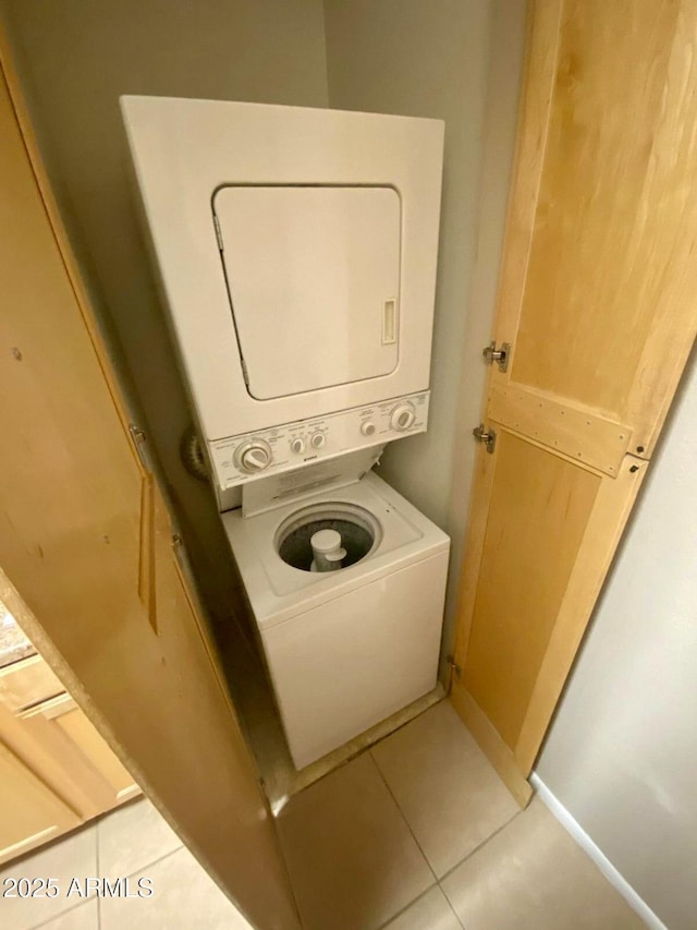 clothes washing area featuring stacked washing maching and dryer and light tile patterned floors