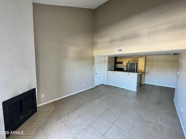 unfurnished living room with light tile patterned floors and a high ceiling