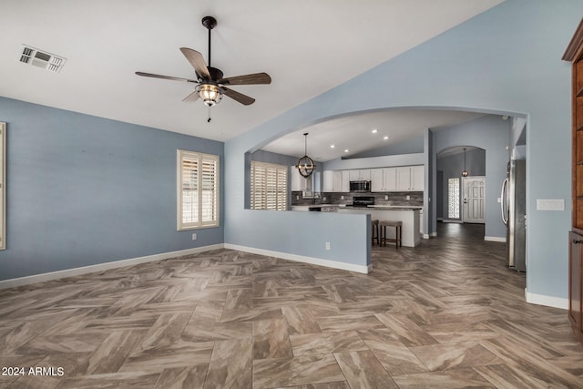 kitchen featuring stainless steel appliances, vaulted ceiling, ceiling fan, backsplash, and white cabinetry