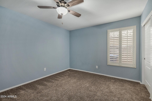 carpeted spare room featuring ceiling fan and baseboards