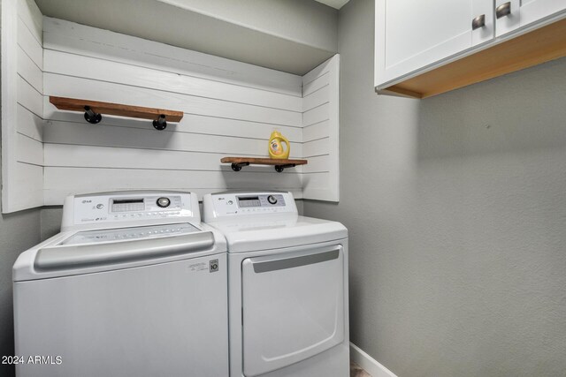 washroom featuring washing machine and dryer and cabinets