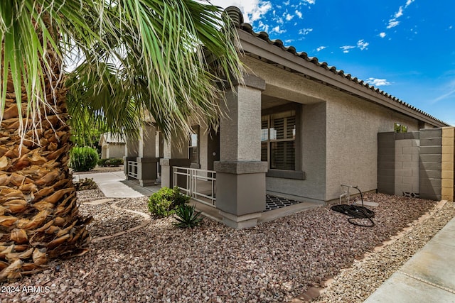 view of property exterior with stucco siding, a tiled roof, fence, and a patio