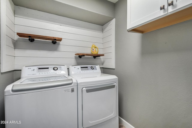 clothes washing area featuring separate washer and dryer, cabinet space, and baseboards