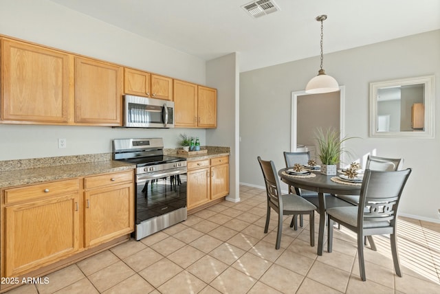 kitchen with hanging light fixtures, stainless steel appliances, light stone countertops, light tile patterned flooring, and light brown cabinets