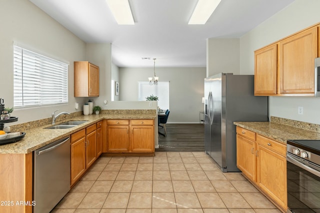 kitchen with light tile patterned flooring, sink, hanging light fixtures, appliances with stainless steel finishes, and kitchen peninsula