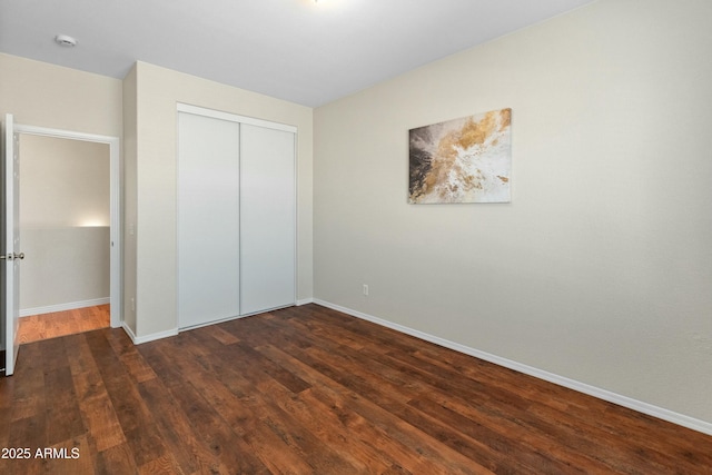 unfurnished bedroom with dark hardwood / wood-style flooring and a closet