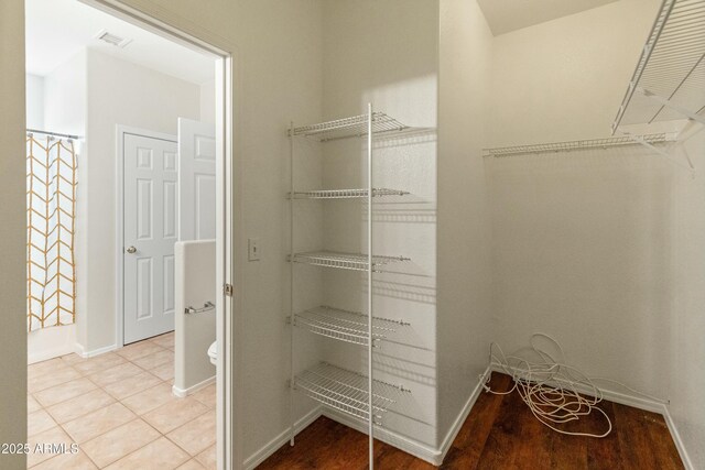 walk in closet with light tile patterned floors