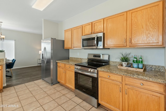 kitchen with light stone counters, decorative light fixtures, light tile patterned floors, a notable chandelier, and stainless steel appliances