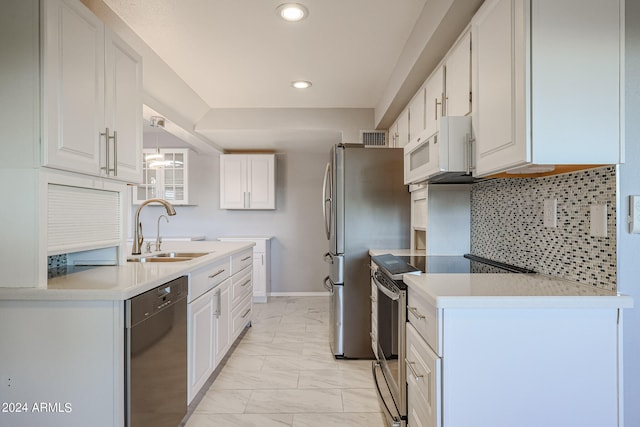 kitchen featuring appliances with stainless steel finishes, white cabinets, sink, and pendant lighting