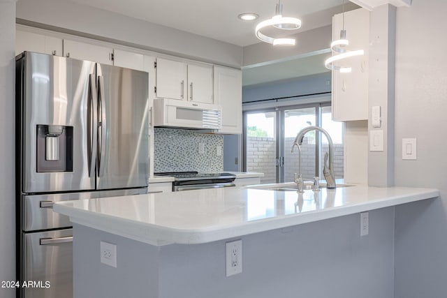 kitchen featuring kitchen peninsula, white cabinets, hanging light fixtures, backsplash, and stainless steel appliances